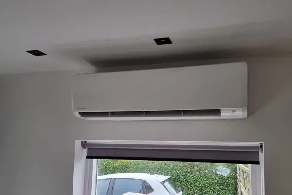 Witte airco boven een raam in een woonkamer