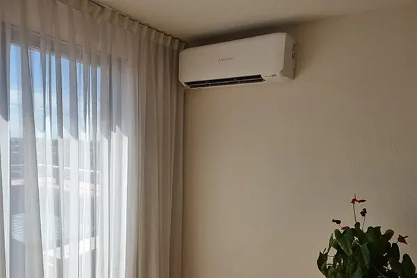 Airco in de hoek naast een raam met vitrage