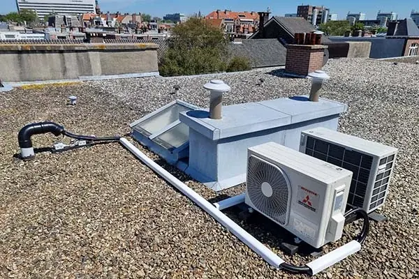 Buitenunits op een plat dak met uitzicht over de stad